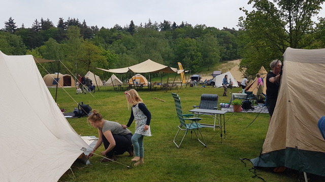 Een vrouw en een meisje zijn samen de haringen van de tent aan het zetten.